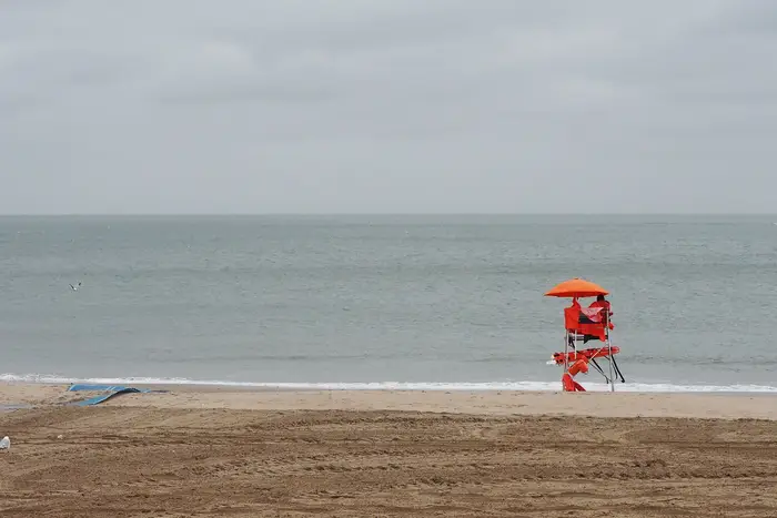 A lifeguard sits in a chair on an empty beach in Coney Island as rain and cold weather. dampen the official opening day of beaches in New York State during Memorial Day weekend in May 2021.